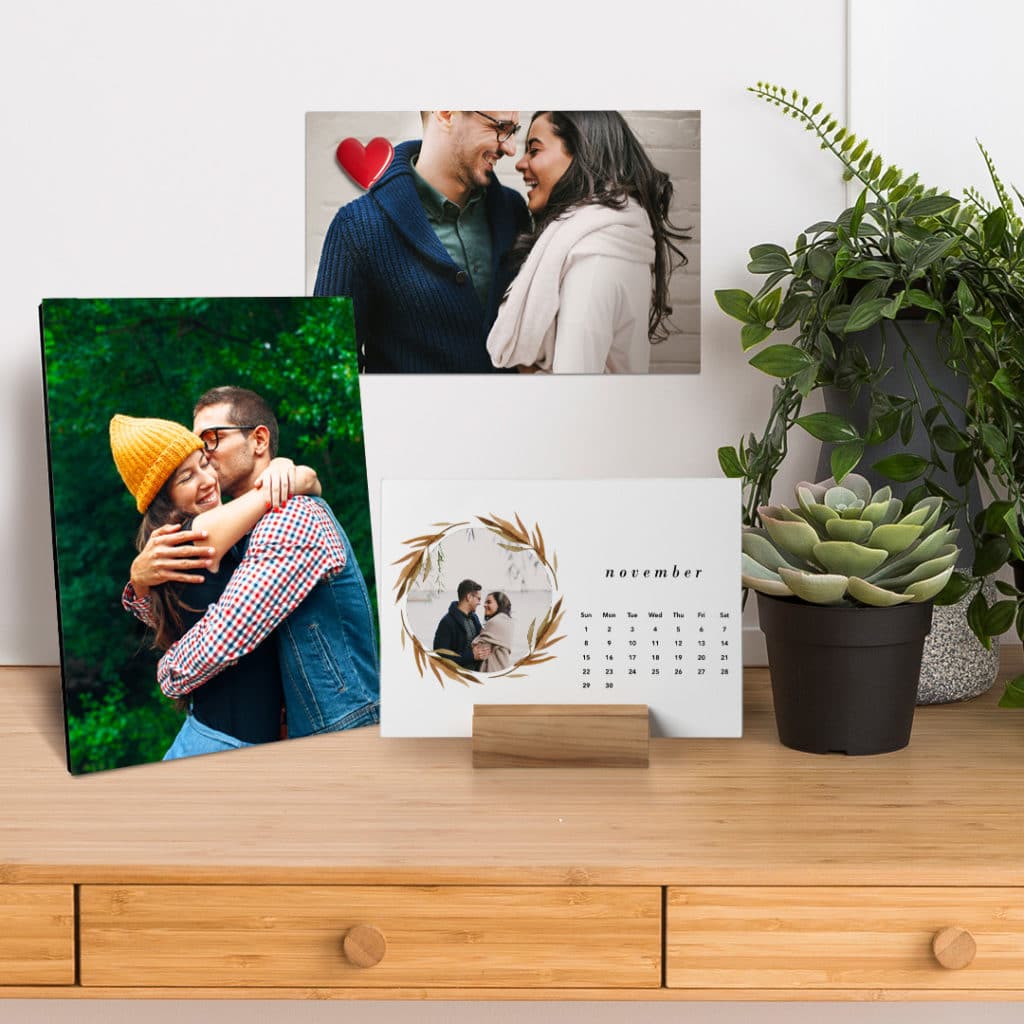 two prints and a wood block calendar on a desk with succulents