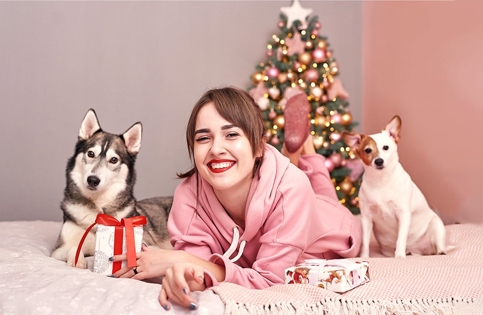 woman posing for picture with two dogs and wrapped gifts