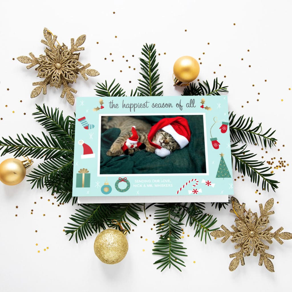 greeting card featuring cat sleeping with santa hat and toy santa, surrounded by christmas decoration