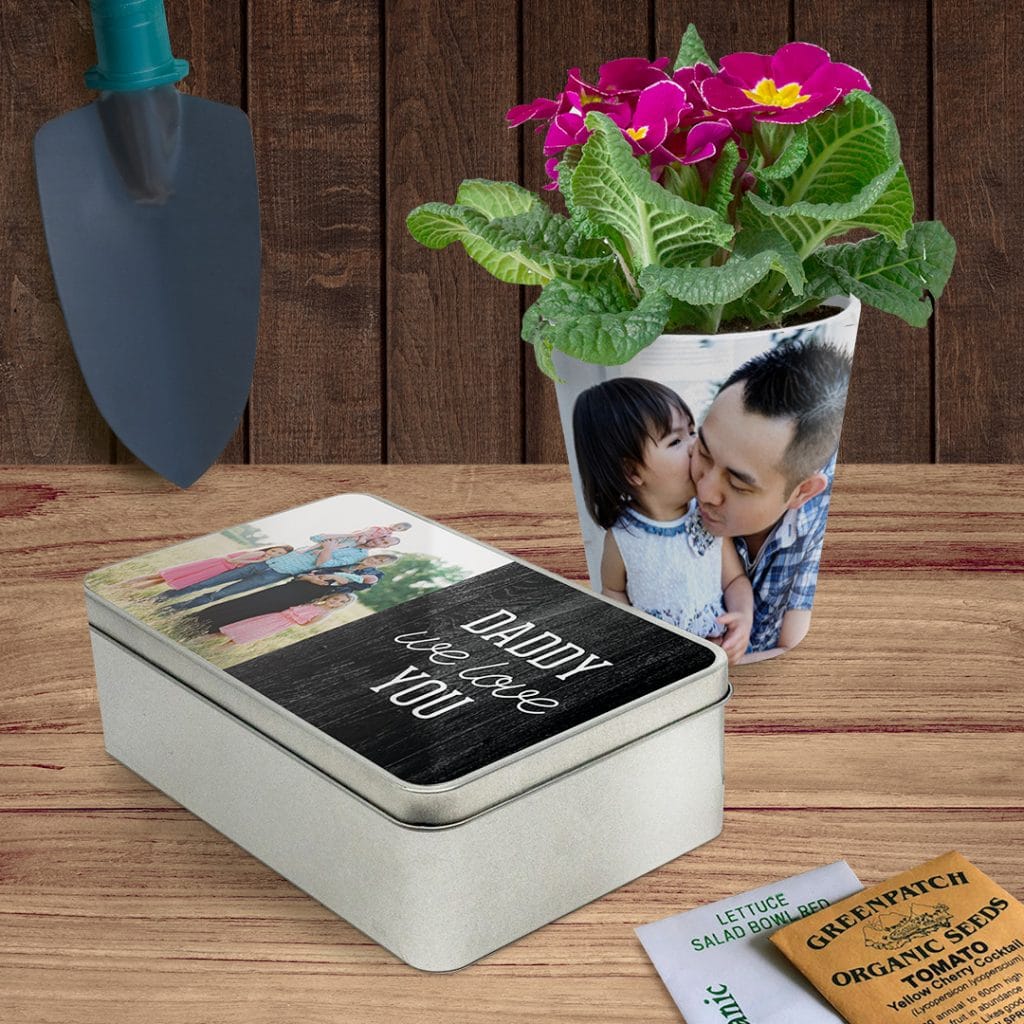A rectangular personalised tin and a photo plant pot on a shed table