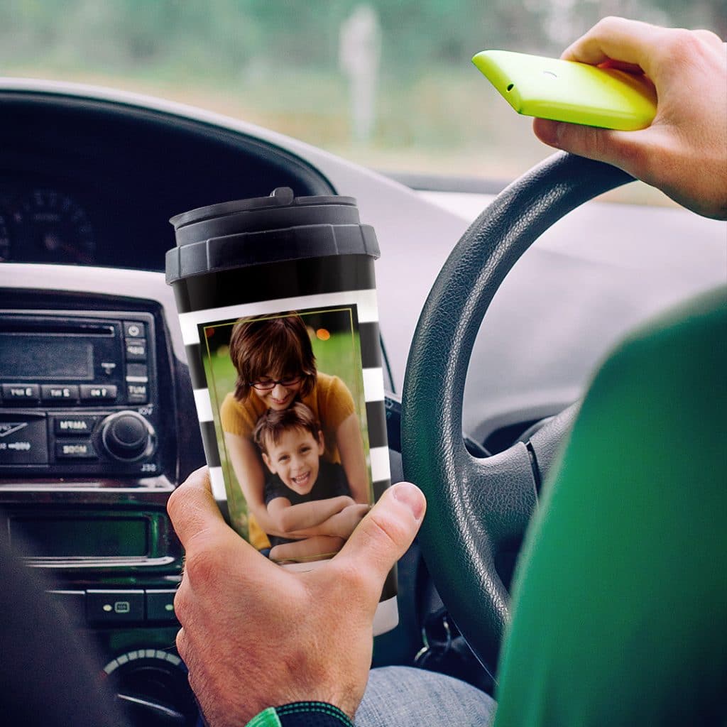 man holding travel mug in car