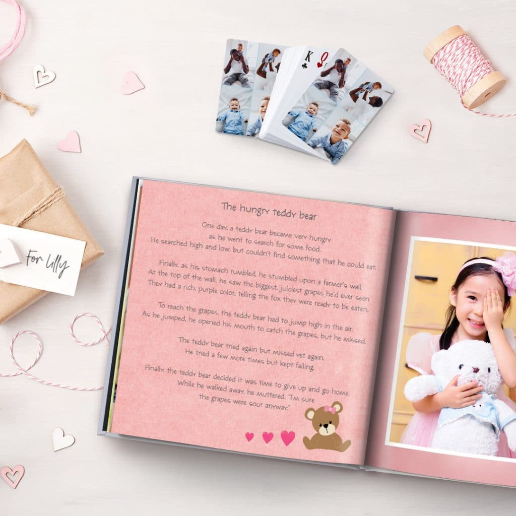 Personalised story book and playing cards for toddlers, displayed on a surface with gift box and paper hearts