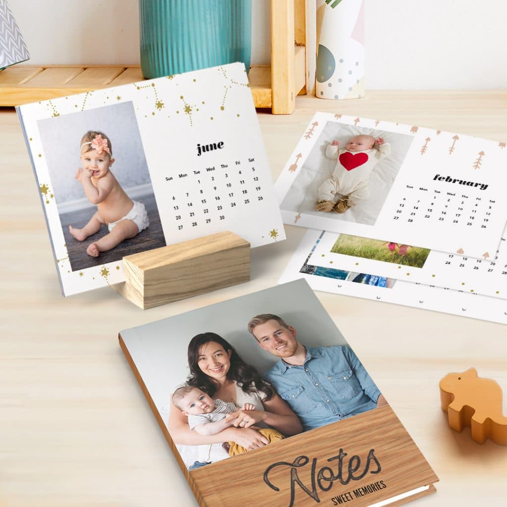 A wood block calendar with baby images and family photo notebook, on a desk