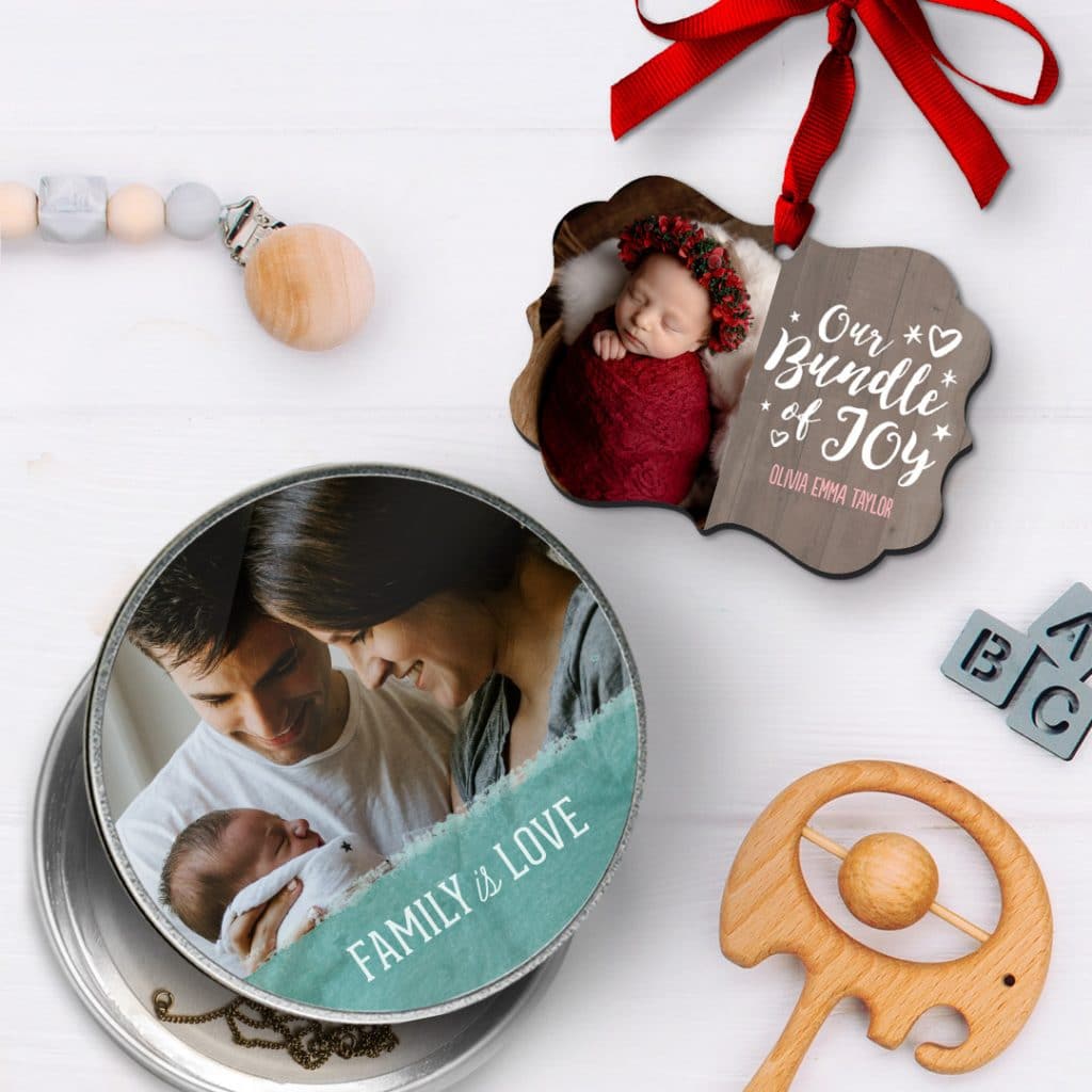 A personalised round tin with a family photo and a baby Christmas ornament