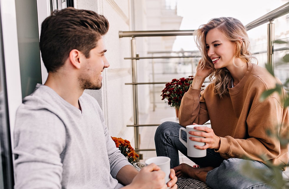 couple on the balcony sipping tea happily during mini break