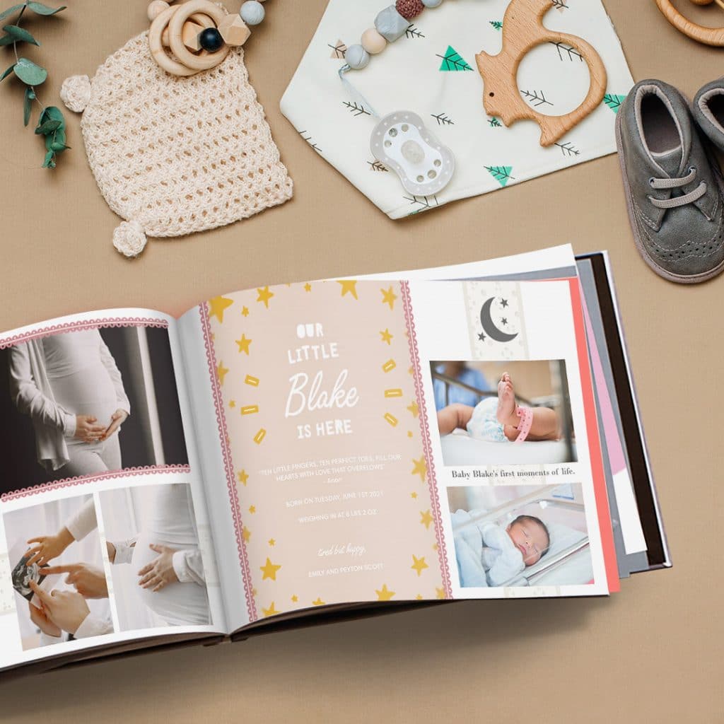 A baby-themed photo book displaying a card design on one of its pages amongst other new baby photos
