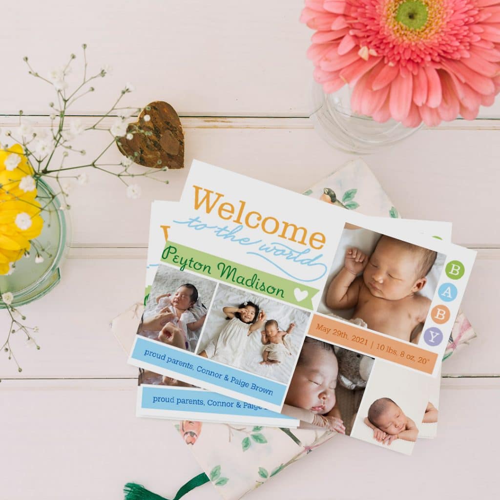 Welcome to the World card birth announcement design laying on a table amongst vases of flowers