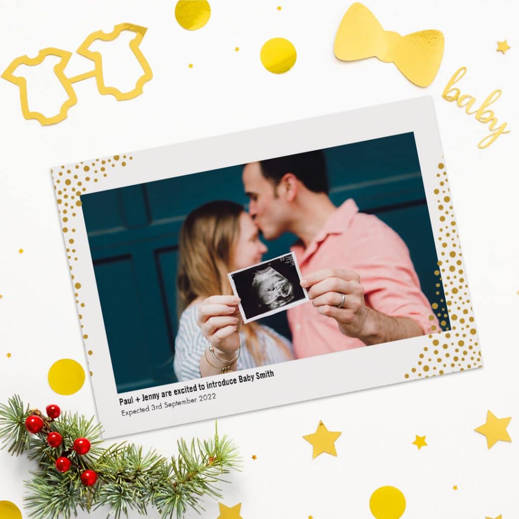 Custom, Christmas themed introducing baby photo card presented on a surface with golden baby props
