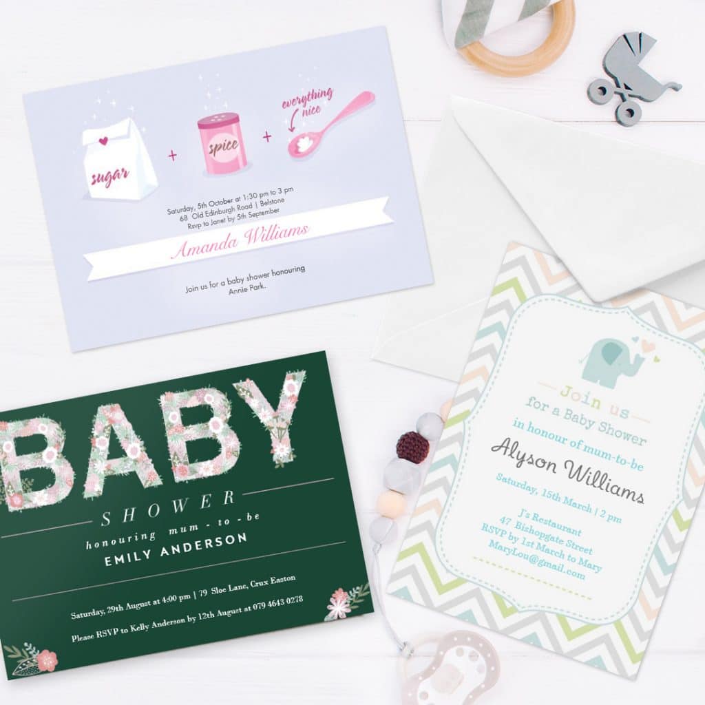 3 personalised baby shower invitation cards displayed on a surface with baby toys