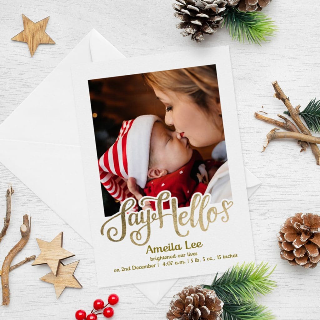 Say hello birth announcement card. Welcoming Christmas baby card on a surface with Christmas pine cones