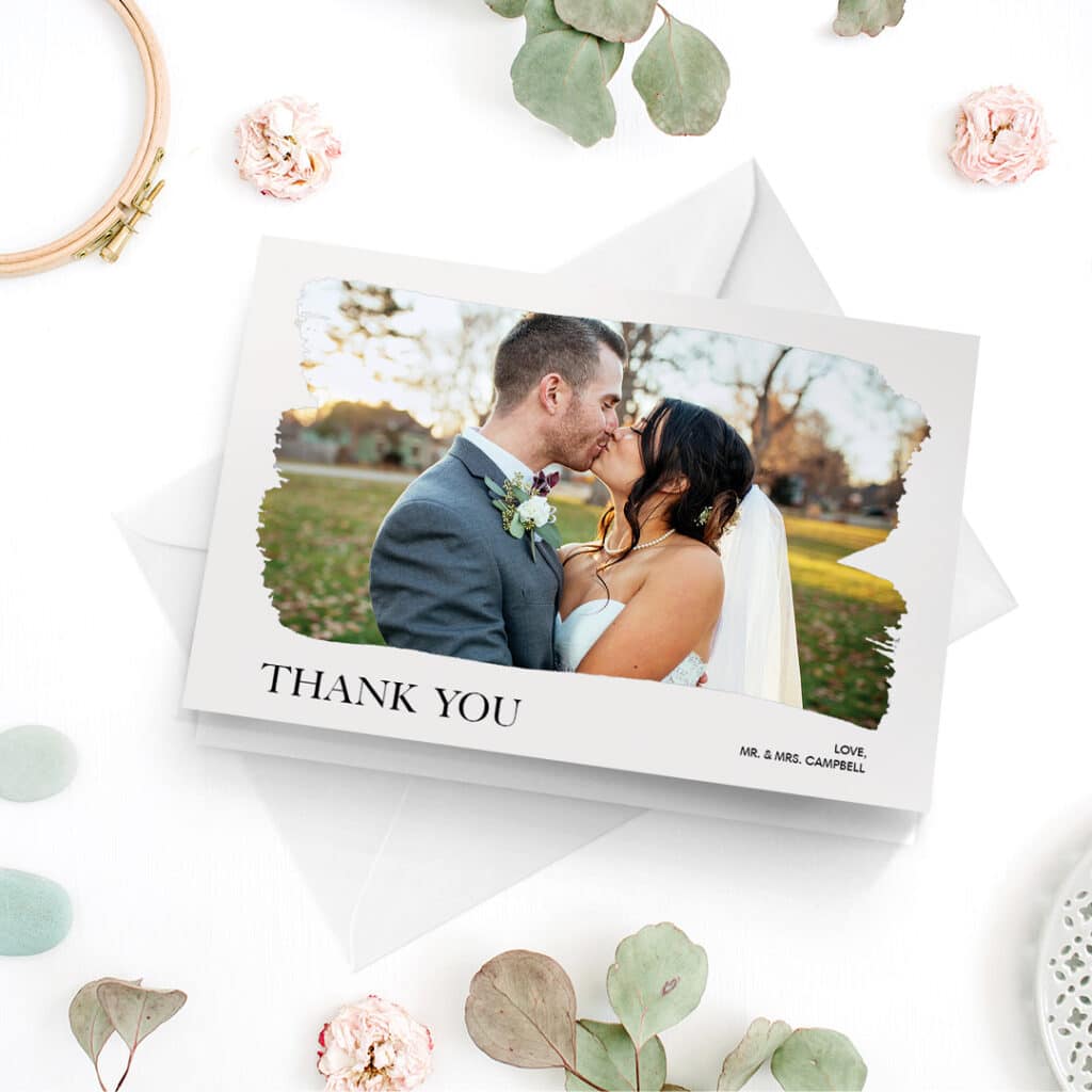 A thank you wedding card with an image of he happy couple kissing