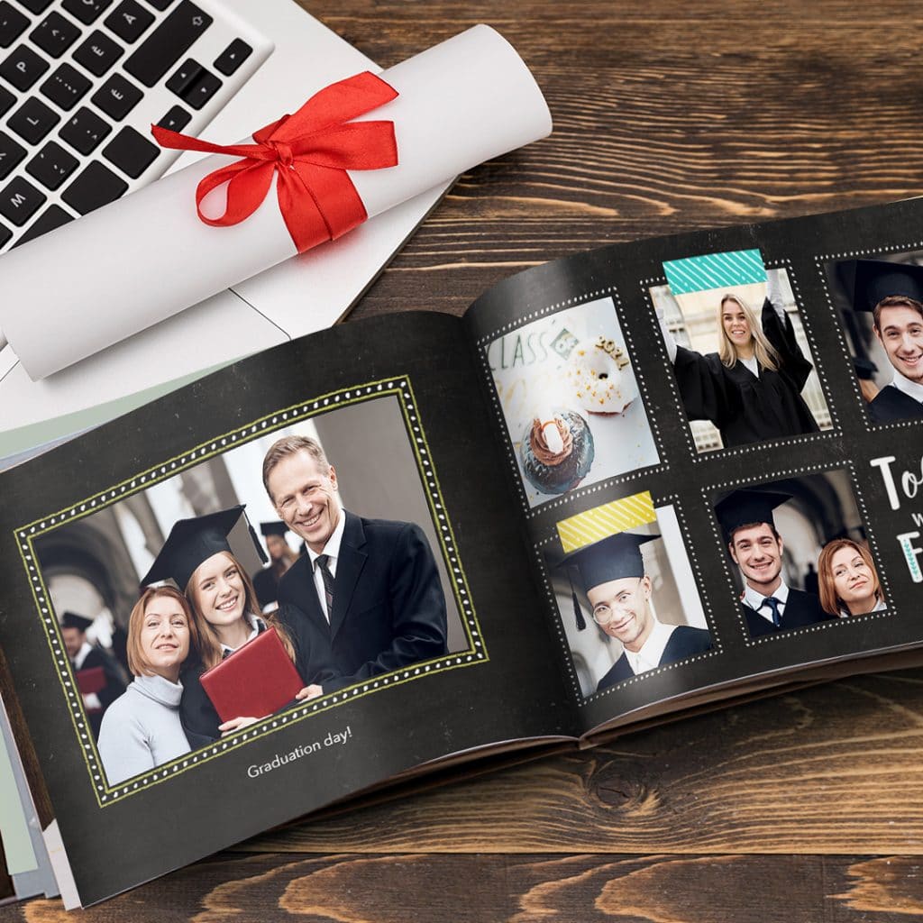 A graduation day photo book with family images presented on a desk next to a diploma