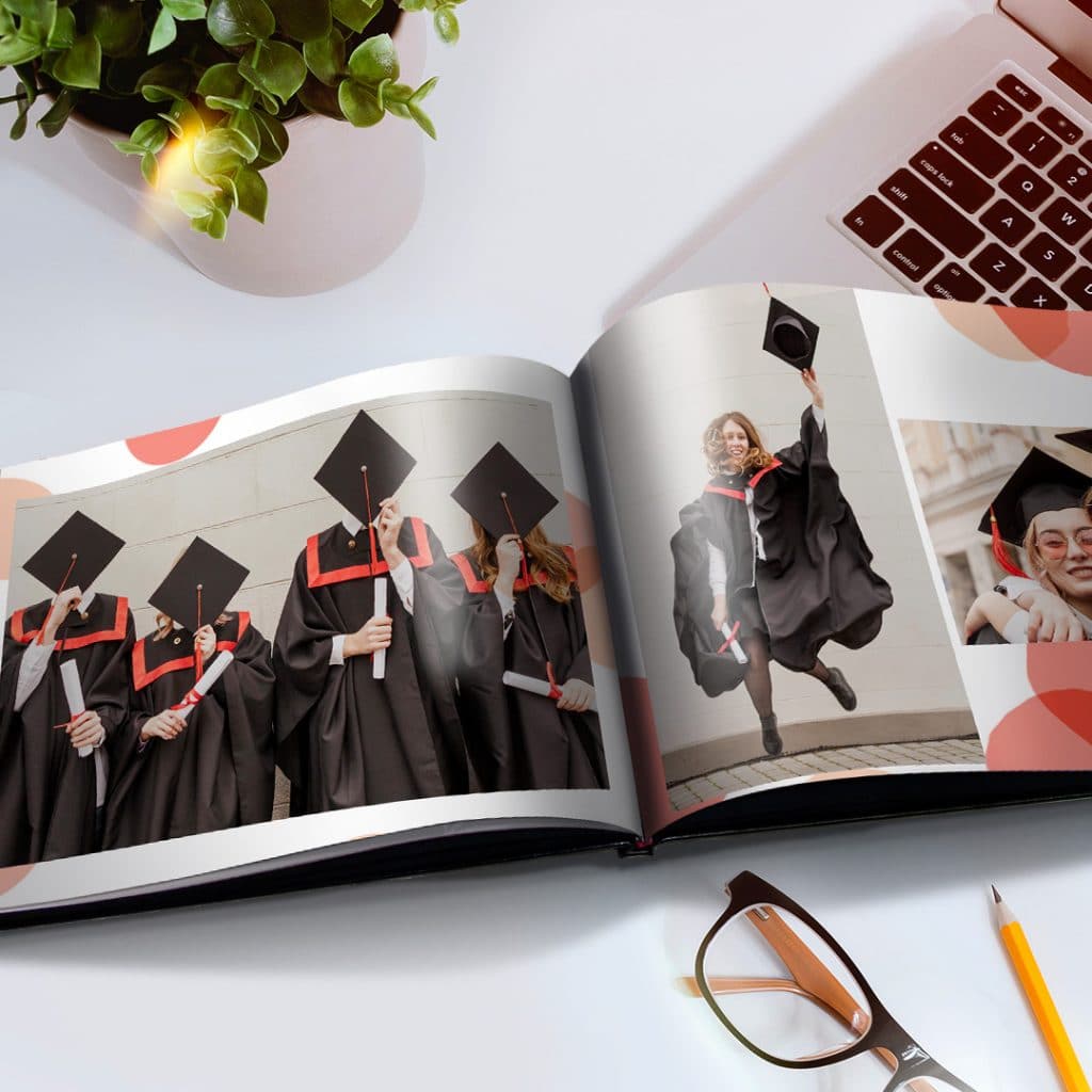 A personalized photo book with images of graduates in gowns shown on an office desk