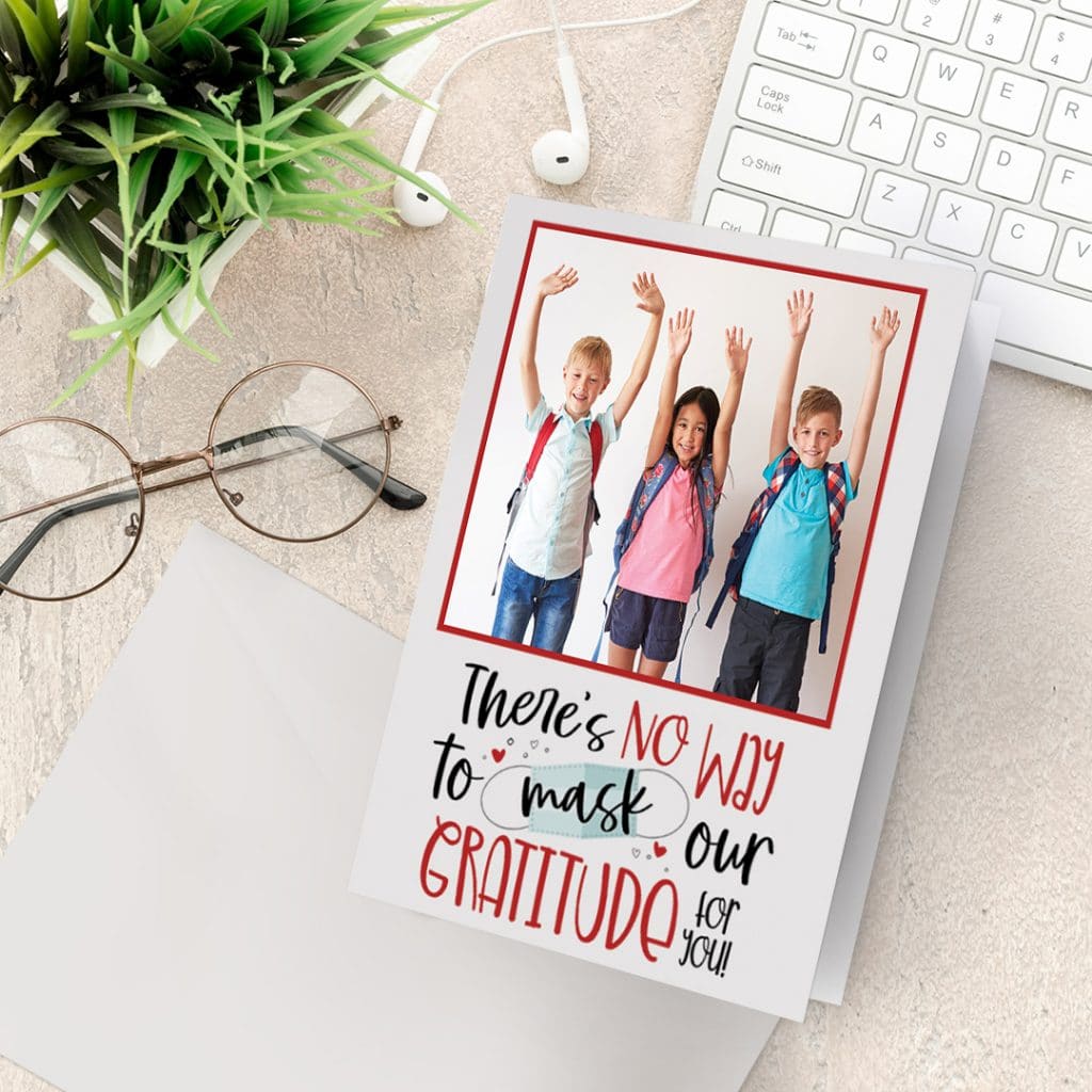 A thank you teacher card on a desk next to a laptop and glasses